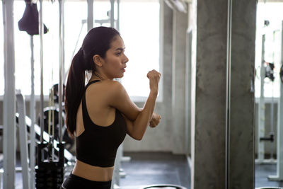 Woman stretching while standing in gym