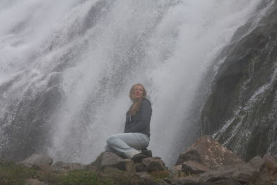 Portrait of young woman sitting on rock