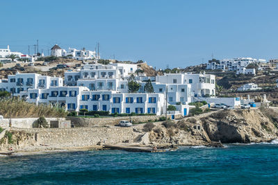 Buildings by sea against clear blue sky