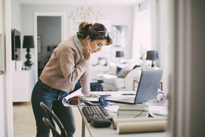 Woman standing by table working from home