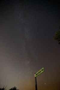 Low angle view of road sign against sky at night