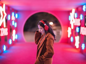 Portrait of young woman standing in city at night