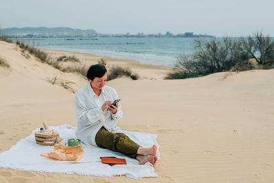 Adult woman on the beach in spring, summer orders online products for a picnic. purchase. fast