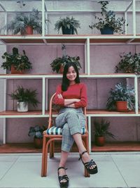 Portrait of smiling woman sitting on seat against plants