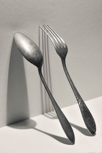 Close-up of fork and spoon on table against wall