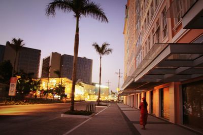 Man walking on road amidst buildings in city