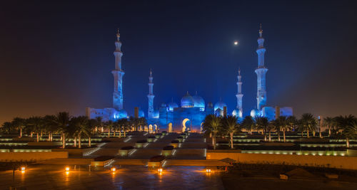 Illuminated grand mosque against sky at night