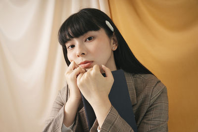 Portrait of beautiful young woman against curtain