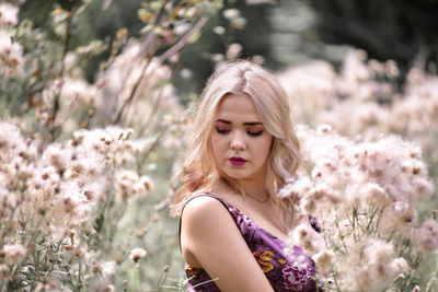 Closed-up of beautiful young woman with blond hair standing amidst flowers