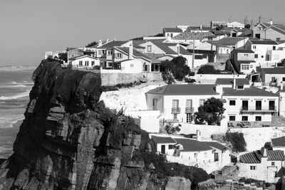Houses on hill by sea against clear sky