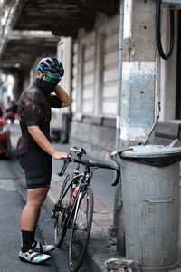 Man with bicycle standing on road