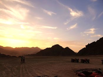 Silhouette people on land against sky during sunset