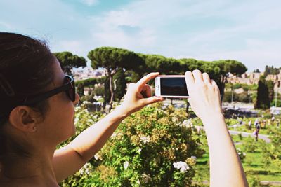 Cropped image of woman photographing through smart phone