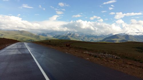 Road leading towards mountains against sky