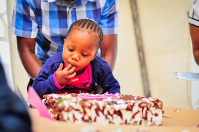 Girl licking birthday cake at home