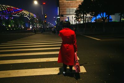 Rear view of woman on road at night