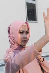 Portrait of beautiful young woman with arms raised