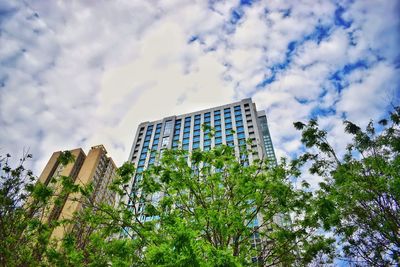 Low angle view of trees and buildings against sky