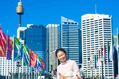 Woman against modern buildings in city against clear sky