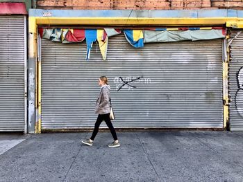 Full length of a boy holding umbrella on footpath