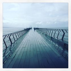 Pier on sea against cloudy sky