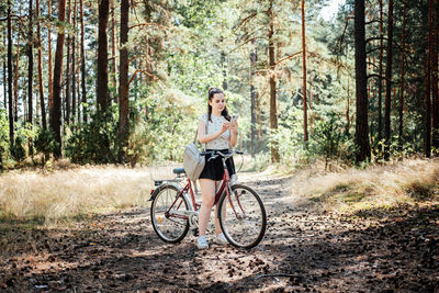 Best cycling apps. bike tracker. young woman with backpack riding bike and looking in cell phone on