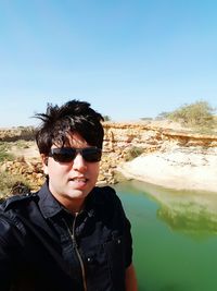 Portrait of man wearing sunglasses against lake