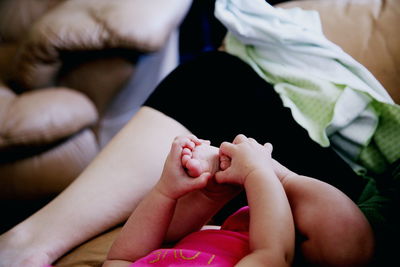 Low section of mother and baby girl on sofa at home