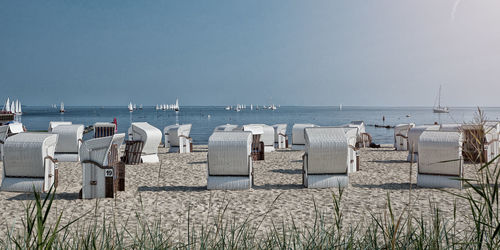 Chairs on wooden posts at beach against clear sky