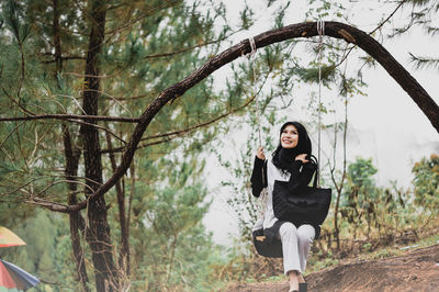 Portrait of young woman standing by tree