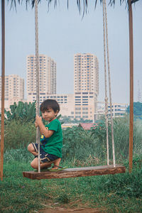 Full length of boy sitting on land against clear sky