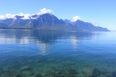 Scenic view of lake and mountains against blue sky