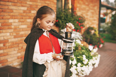 Girl holding ice cream standing against wall