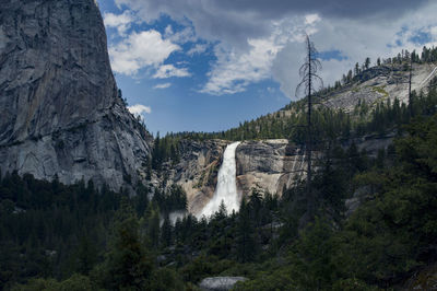 A small spot light of sun bursts through the clouds to illuminate nevada falls in yosemite.