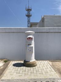 Telephone booth by building against sky