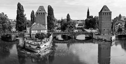 Arch bridge over river against buildings in city