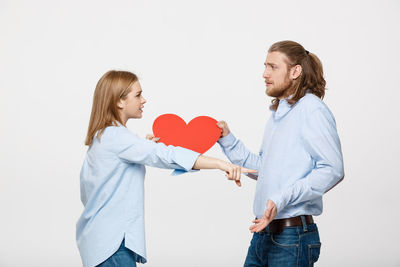 Young couple holding heart shape over white background