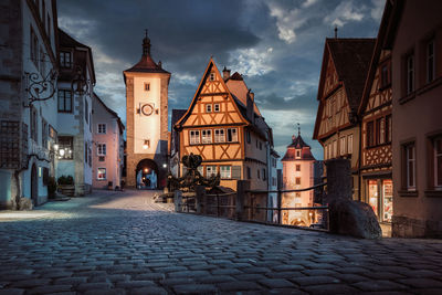 Street amidst buildings against sky at dusk