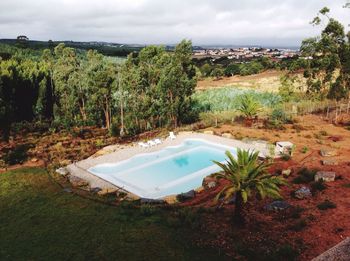 Scenic view of pool in green landscape against cloudy sky