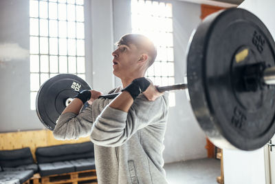 Young man lifting dumbbell exercising in gym