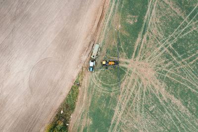 Drone view of a tractor with a sprayer stands near a tractor with a water tank. 