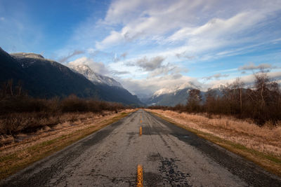 Empty road towards mountains along countryside landscape