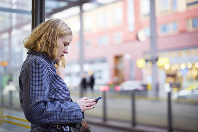 Woman using cell phone at bus stop