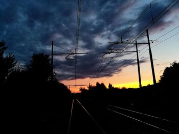 Railroad tracks against dramatic sky during sunset