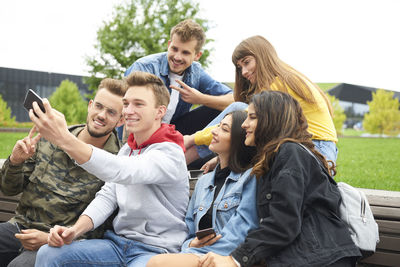 Rear view of friends sitting on smart phone