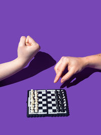 Cropped hand of woman holding jigsaw piece against blue background