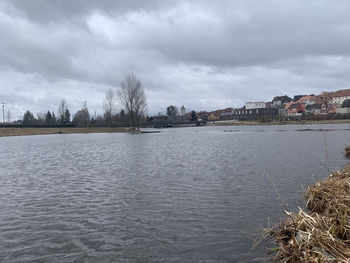 Scenic view of river by city against sky