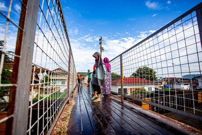 Rear view of man walking on footbridge