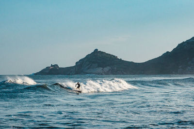 Scenic view of sea and mountains against clear sky