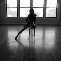 Rear view of man sitting on floor at home